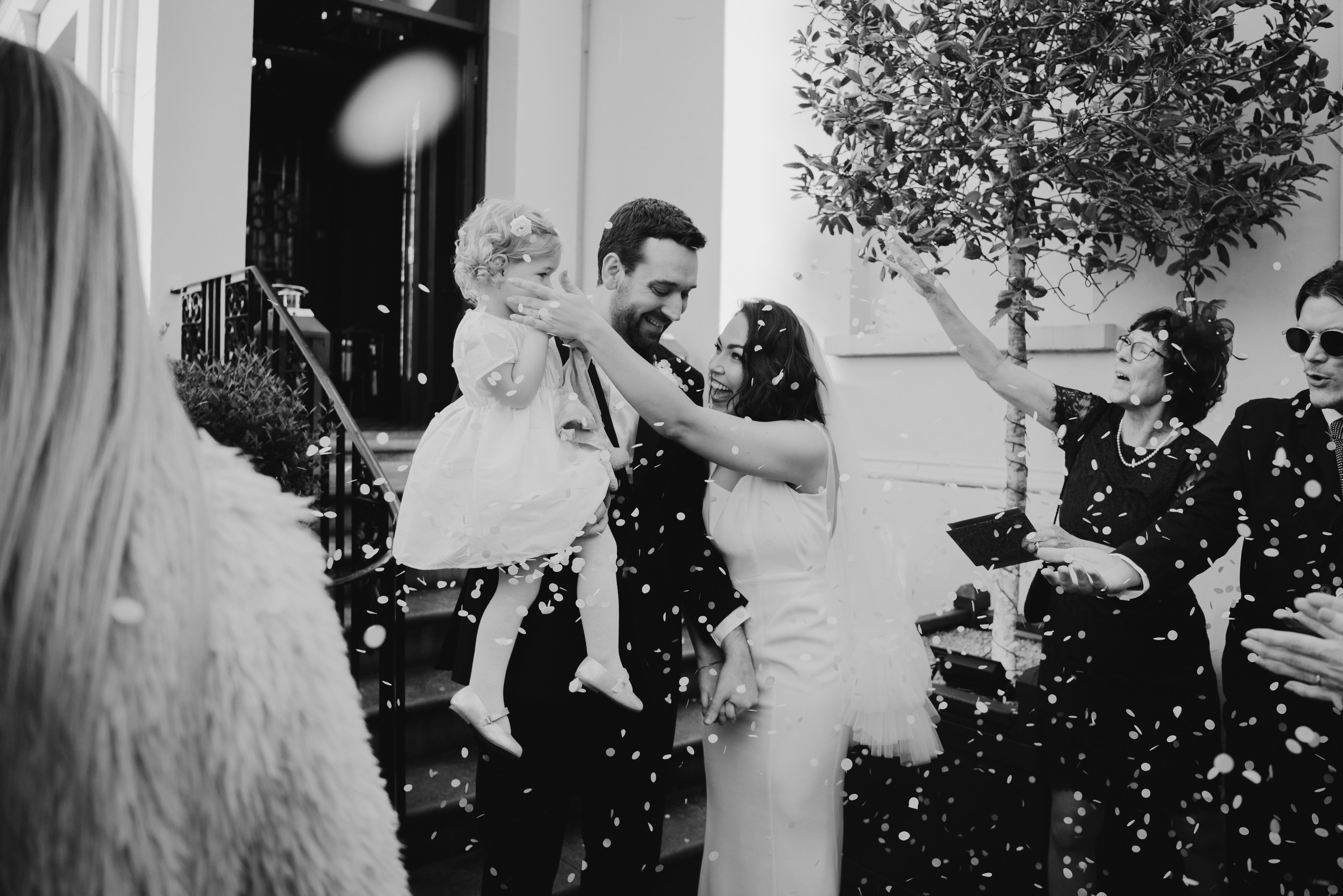 Happy couple smiling in confetti outside wedding venue