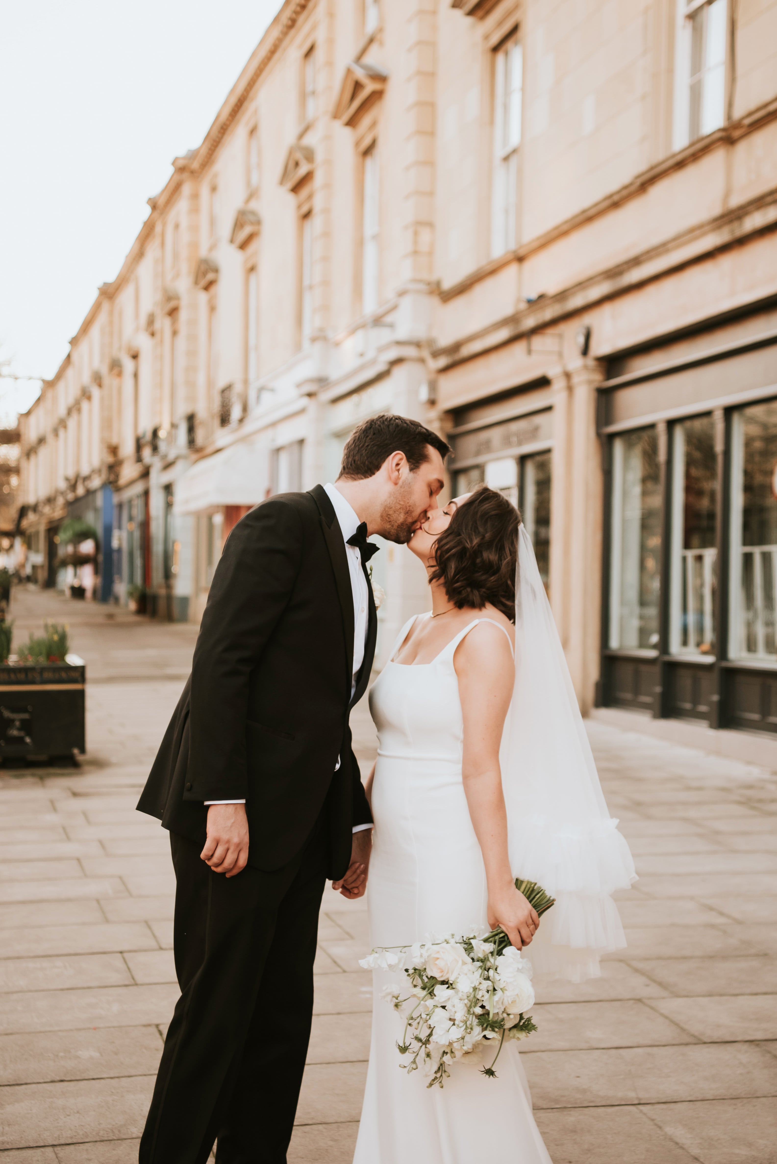 Happy wedding couple Laurie and Matt kiss outside the venue