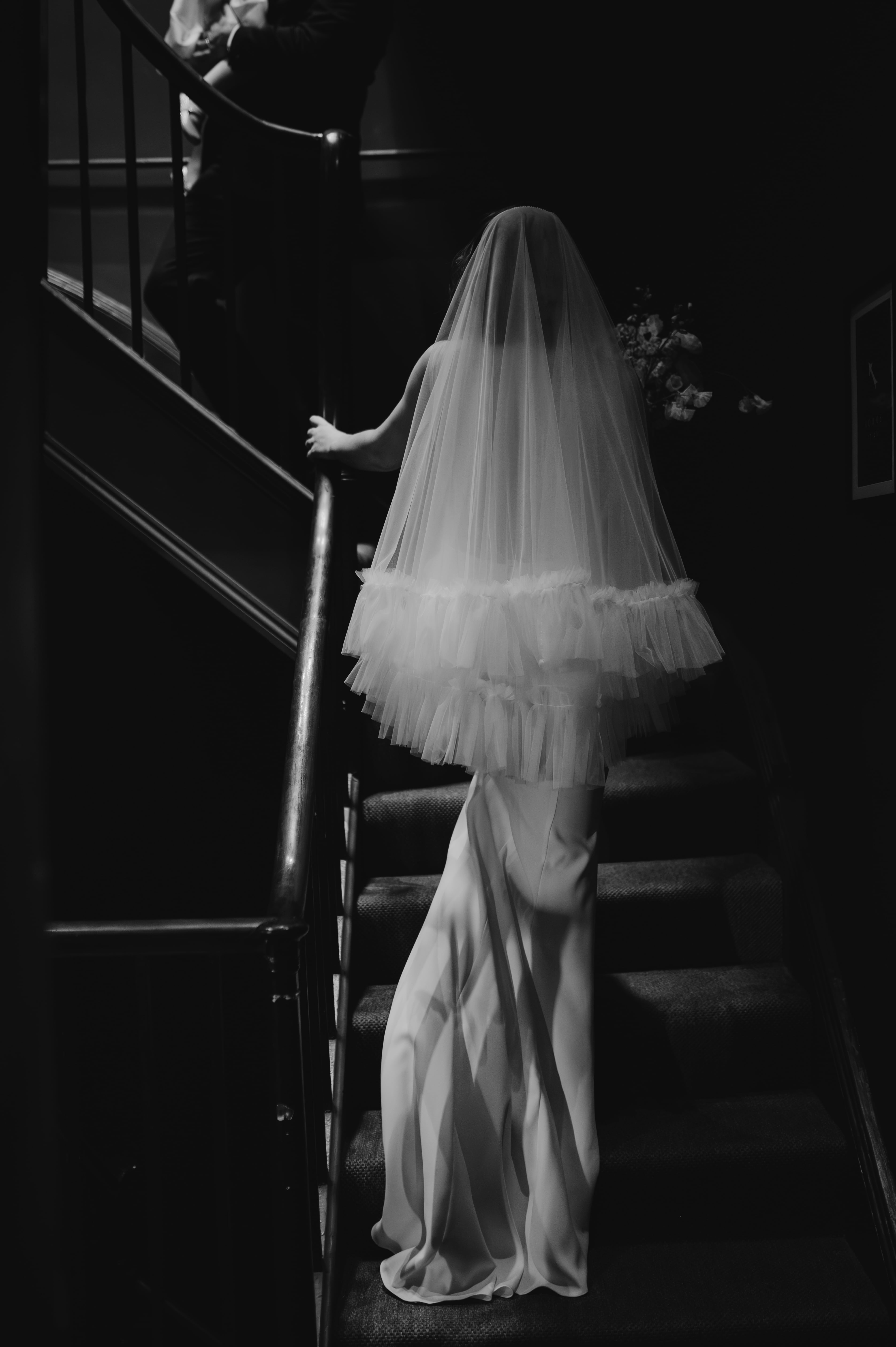 Black and white shot of bride walking up stairs
